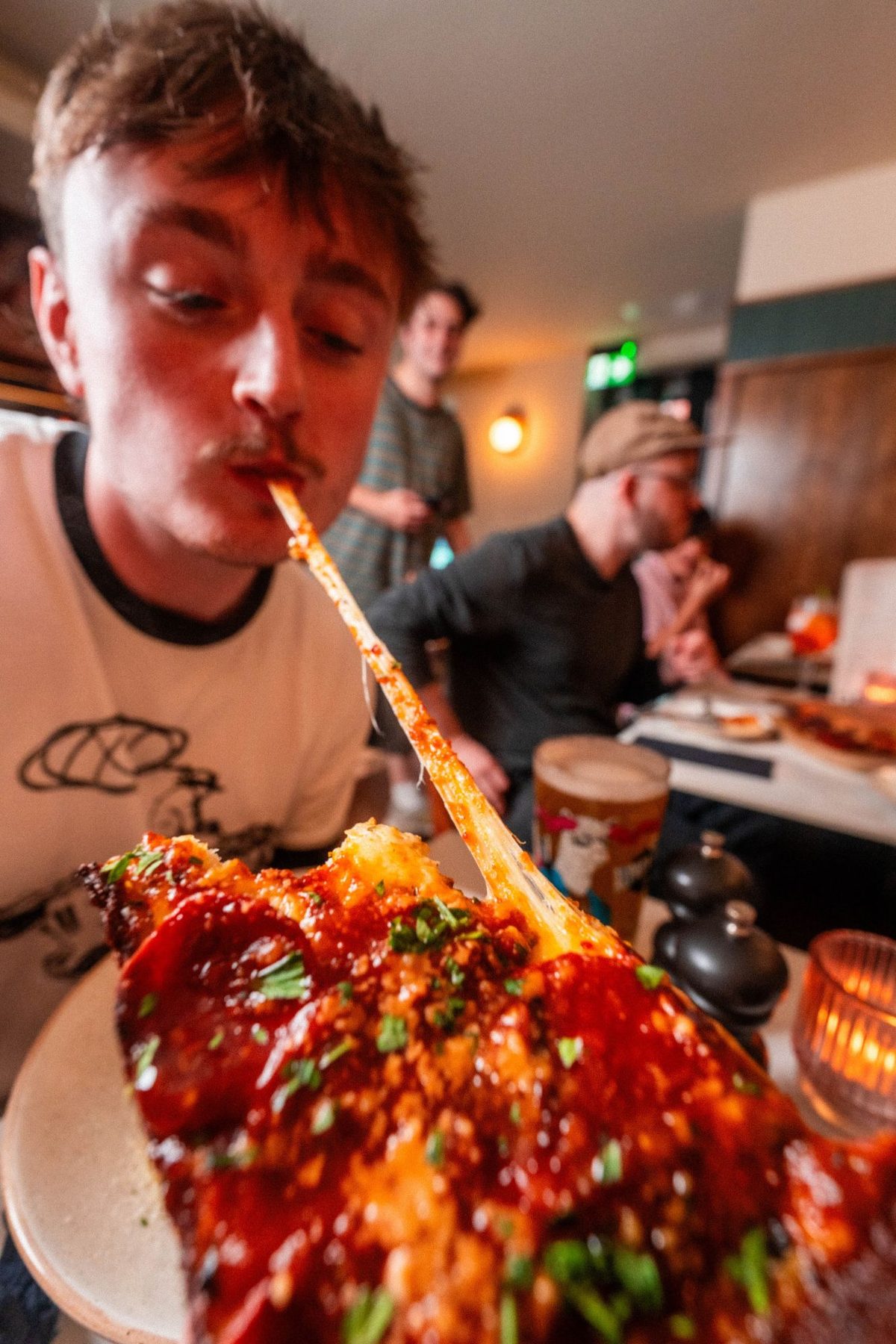 A guest pulling a long string of cheese from a slice of deep-dish pizza